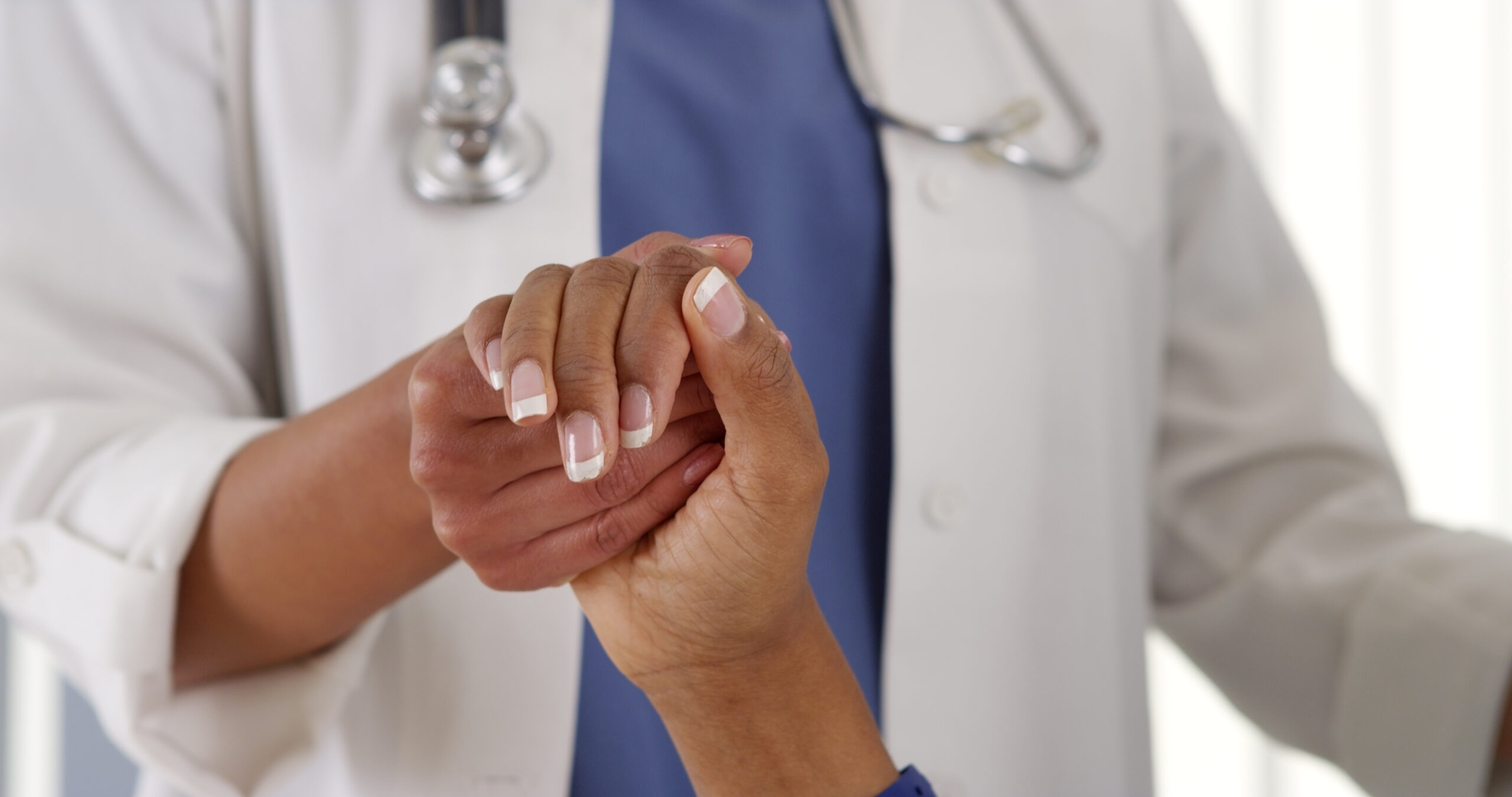 Medical care provider holding patient's hand